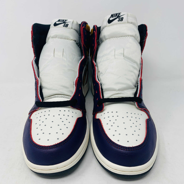 A brand new Jordan 1 High SB LA to Chi sneaker rests on a black Jordan box with a red logo. This authentic high-top shoe features multi-colored accents of purple, yellow, white, and red, with the label proudly reading 1985 Air Jordan 1.