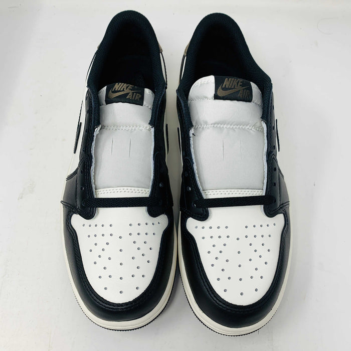 A pair of Jordan 1 Retro Low OG Mocha sneakers, seen from above on a white surface, featuring a perforated white toe box, black overlays, and a visible Jordan logo on the tongue. Box condition is good.