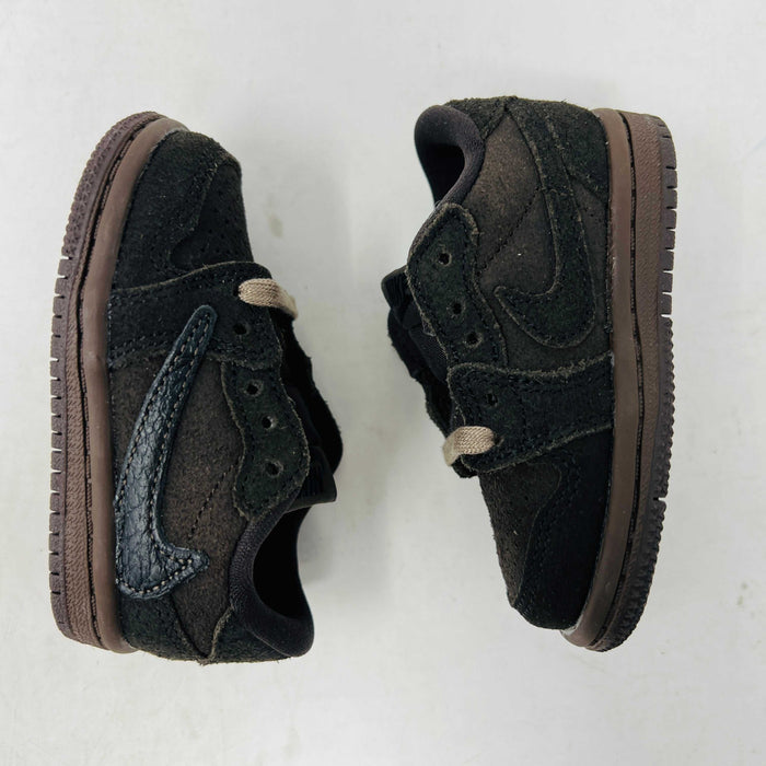 A Jordan 1 Retro Low OG SP Travis Scott Velvet Brown (TD) sneaker with a unique swoosh design sits on a white shoebox. It includes extra pink and black laces, is 100% authentic, brand new, and ready to elevate your style with its sleek look.