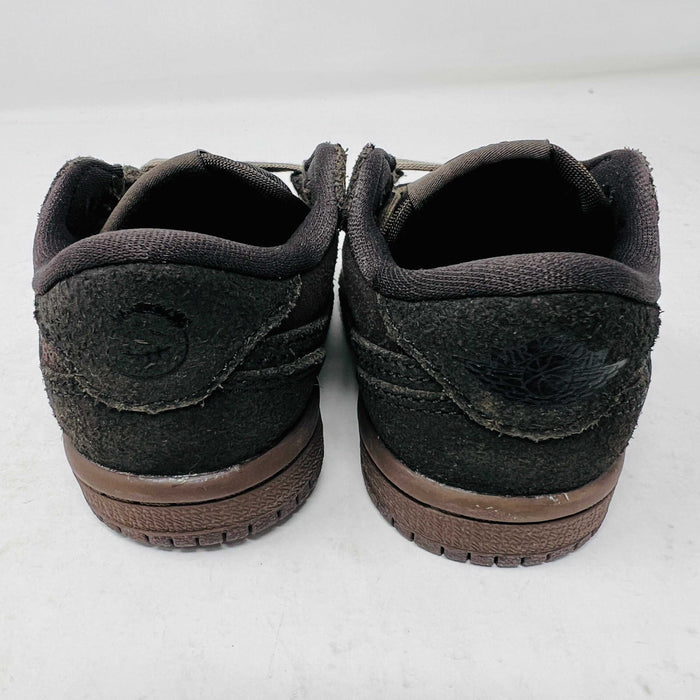 A Jordan 1 Retro Low OG SP Travis Scott Velvet Brown (TD) sneaker with a unique swoosh design sits on a white shoebox. It includes extra pink and black laces, is 100% authentic, brand new, and ready to elevate your style with its sleek look.