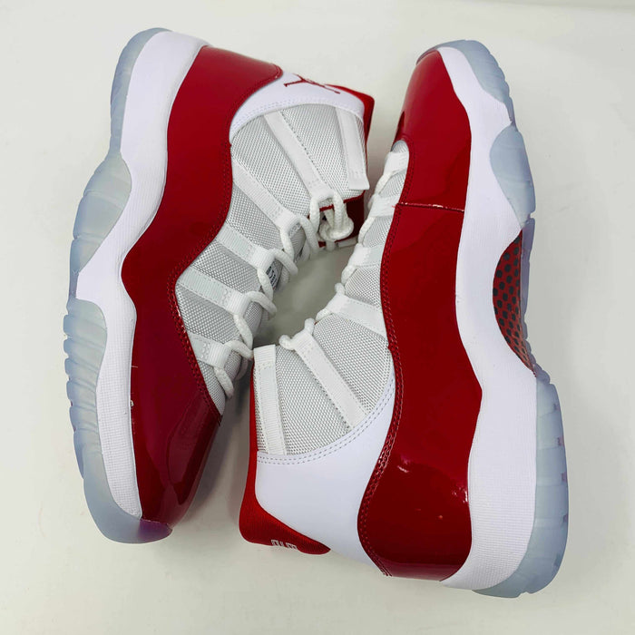 Jordan 11 Retro Cherry (2022) sneakers with white and red colorway, patent leather mudguard, and full-length Air-Sole unit.
