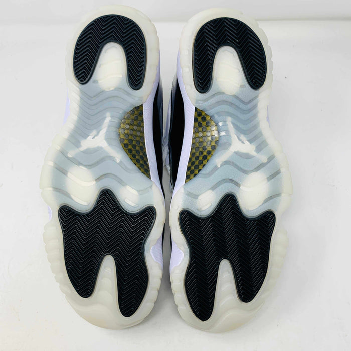 The Jordan 11 Retro DMP Gratitude (2023) features high-top sneakers in a white-black colorway with shiny accents. They have white laces, a crisp white midsole, and a translucent outsole, adorned with a small golden ankle logo and come in a sleek black box.