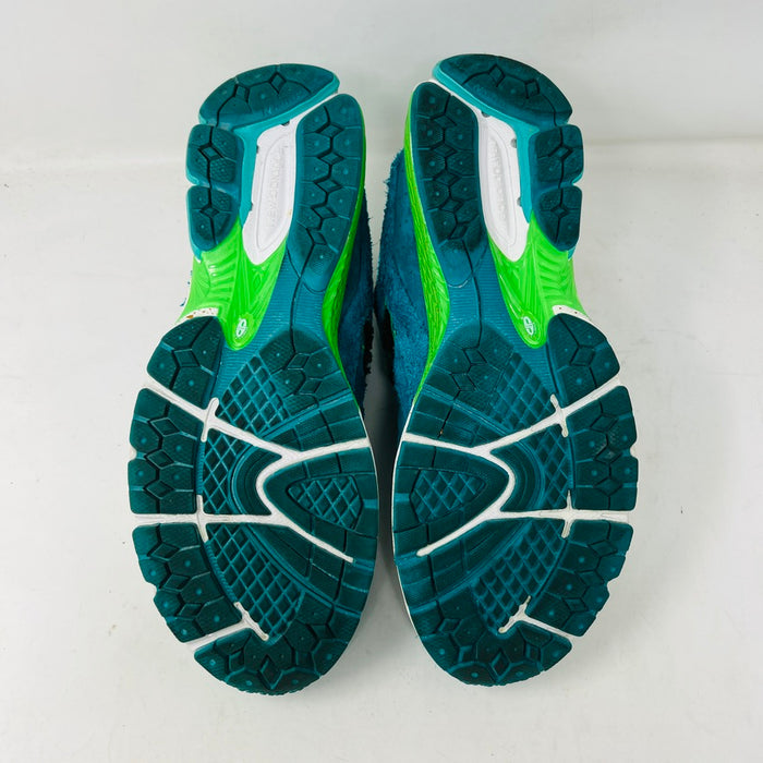 A pair of New Balance 2002R by Salehe Bembury, in colorful teal, pink, and green accents, sits atop a shoebox. Two extra lace sets—pink and green—are in front. The shoebox label details the size and style; the box is in good condition with a clean design.