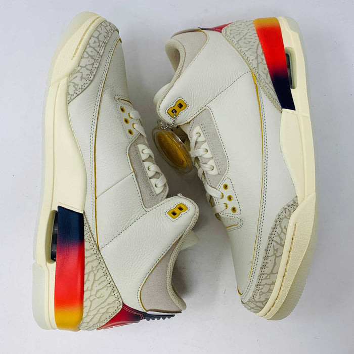 A close-up of the Jordan 3 Retro SP J Balvin Medellín Sunset sneakers by Jordan, showcasing white leather, gray elephant print details, and vibrant gradient heel panels in yellow, orange, and red. The shoes are arranged sole to sole on a white background.