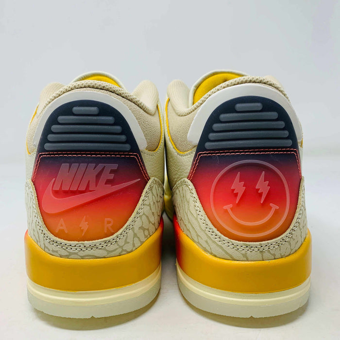 Rear view of the Jordan 3 Retro SP J Balvin Medellín Sunset sneakers, showing off-white uppers with vibrant orange and yellow gradient heels. The left heel displays the Jordan logo, while the right heel features a smiley face with lightning bolt eyes.
