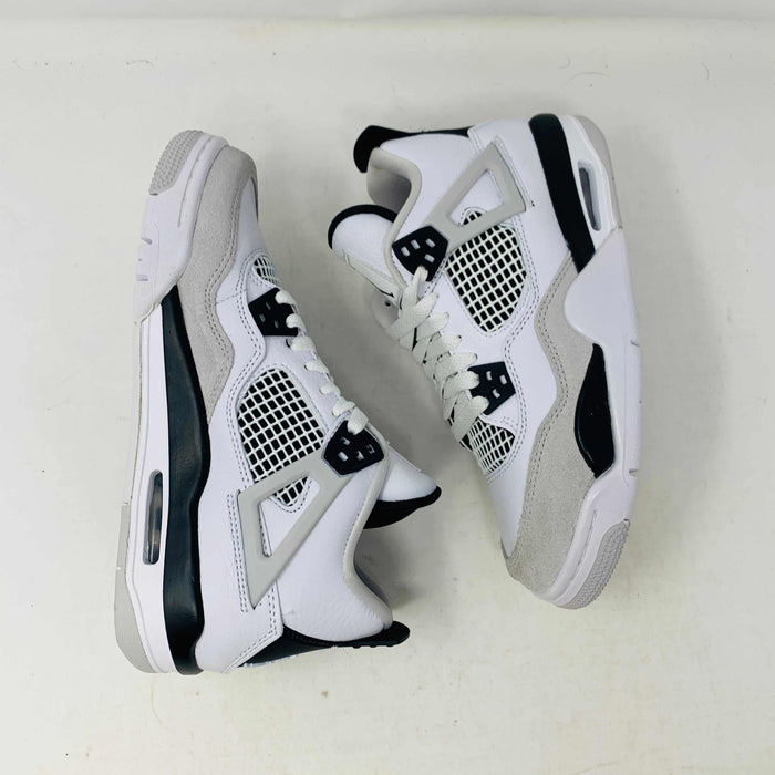 The Jordan 4 Military Black GS sneakers, featuring distinctive side netting and a logo on the tongue, are brand new and authentic in white and gray with black accents. They face forward on a white surface against a plain background, embodying modern style.