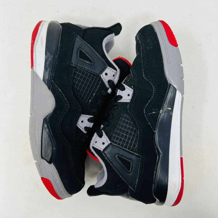 The Jordan 4 Retro Bred (2019) (PS) in black and red, featuring clean uppers with a white midsole and gray accents, sits on its original black shoebox. The box displays size, product details, and the iconic Jumpman logo, underscoring these authentic shoes from Jordans 2019 collection.
