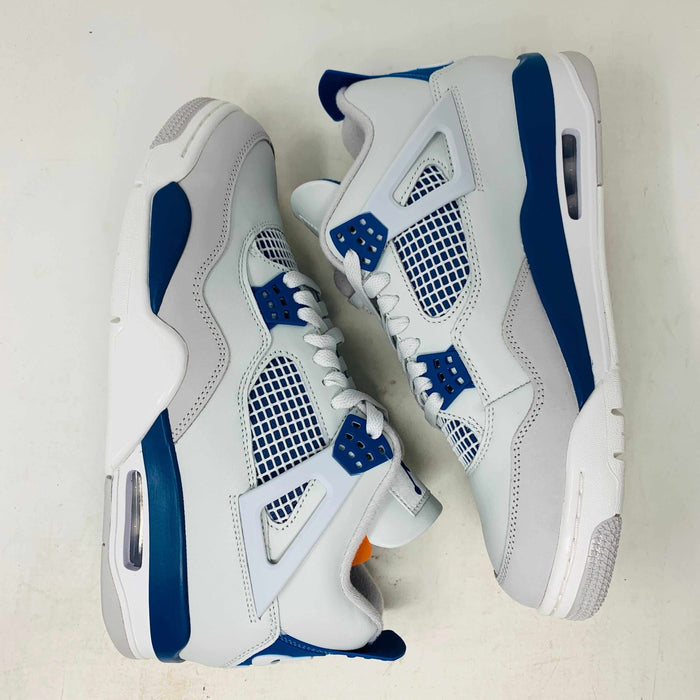 The Jordan 4 Retro Military Blue (2024) sneaker, with white and blue mesh details and a visible air cushion, rests on a black speckled NIKE AIR box with bold orange text. It is 100% authentic, including orange tags, ensuring it’s brand new.