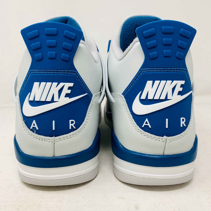 The Jordan 4 Retro Military Blue (2024) sneaker, with white and blue mesh details and a visible air cushion, rests on a black speckled NIKE AIR box with bold orange text. It is 100% authentic, including orange tags, ensuring it’s brand new.