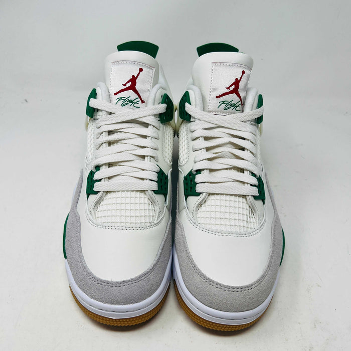 The Jordan 4 SB Pine Green sneakers feature a white and green design with red logo accents, gum-colored soles, and showcase mesh and suede details from the front.