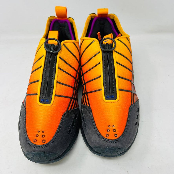 The Nike Air Max Sunder SP Kids of Immigrants Sunrise sneakers in bright orange and black feature a grid pattern with blue accents. An authentic swoosh and a circular K-I design mark the shoes and the orange box, highlighting their uniqueness.