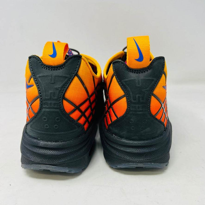 The Nike Air Max Sunder SP Kids of Immigrants Sunrise sneakers in bright orange and black feature a grid pattern with blue accents. An authentic swoosh and a circular K-I design mark the shoes and the orange box, highlighting their uniqueness.