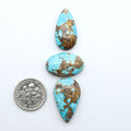 Black Jack turquoise cabochons, blue-green color with black matrix, polished stones on a white background with a US dime for scale