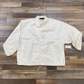 God Essentials Coaches Jacket Cloud Dancer, brand new condition, cream white color displayed flat.