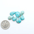 Fox Turquoise cabochons, polished gemstones with natural matrix on a white background, with a US dime for scale