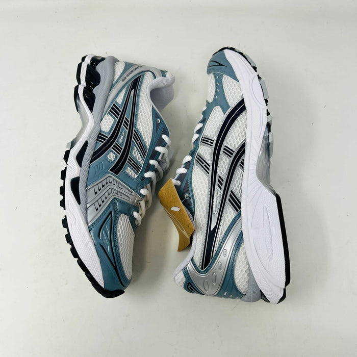 The ASICS Gel-Kayano 14 White Fjord Grey running shoe stands on a brown ASICS box, featuring intricate designs, a breathable mesh upper, and a cushioned thick sole for support. Its 100% authentic.