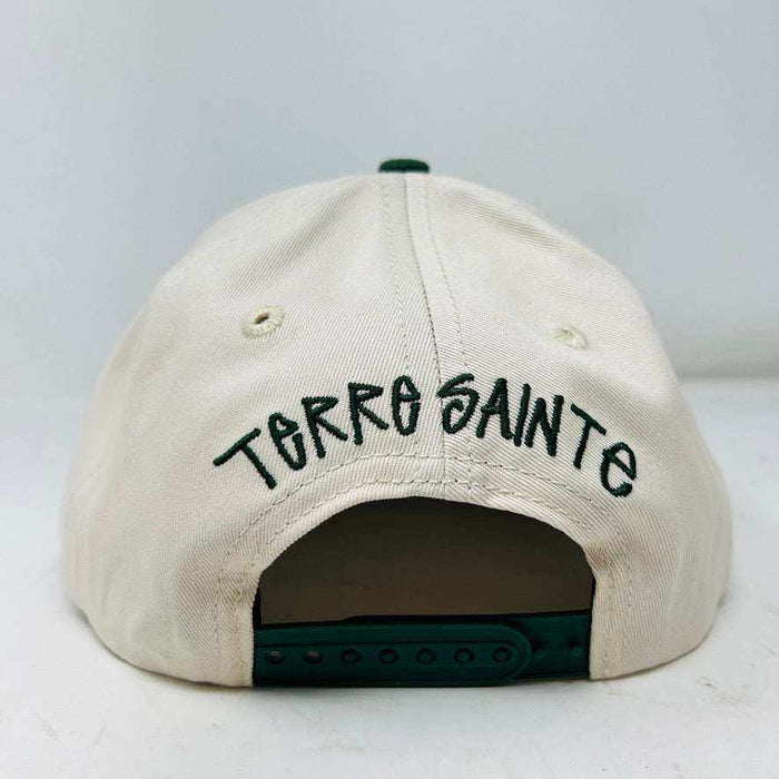 The Holy Ground Stussy Hat by Holy Ground is a streetwear accessory with HOLY GROUND embroidered in black on its white front panel, complemented by a green bill for a fresh touch.