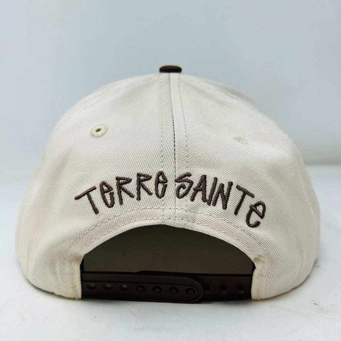 The Holy Ground Stussy Hat by Holy Ground is a streetwear accessory with HOLY GROUND embroidered in black on its white front panel, complemented by a green bill for a fresh touch.