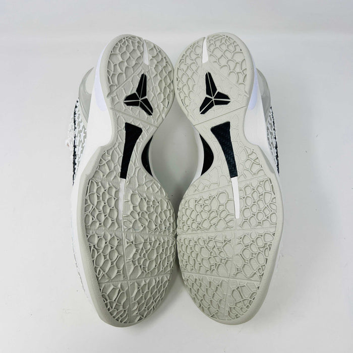 The Nike Kobe 6 Protro Sail All-Star shoes, featuring white textured patterns and black swoosh details with star designs, are elegantly displayed on a sleek black shoebox.