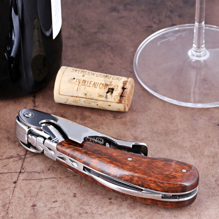 Laguiole Magnum Amourette Corkscrew, close-up of polished steel and rich wood handle on brown surface.