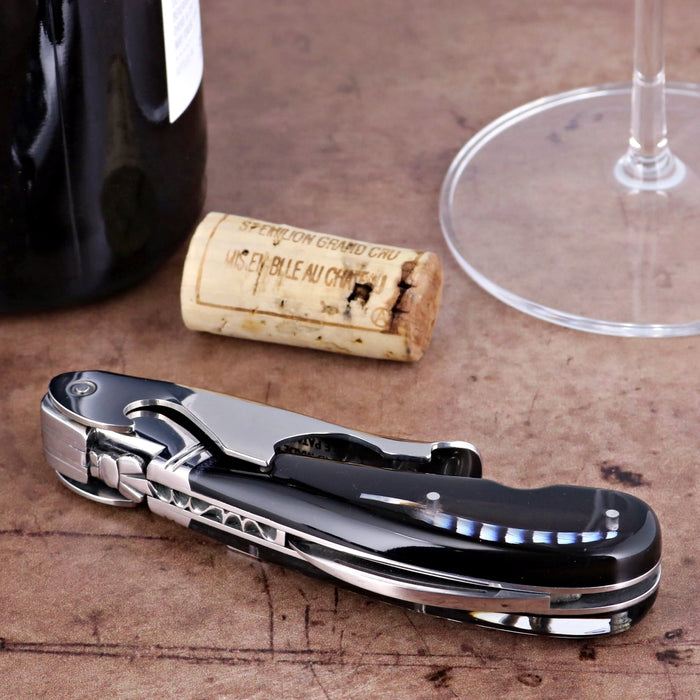 Laguiole Magnum Two-Step Corkscrew, black handle with genuine feather inlay, side view on wood.