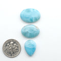 Larimar stone cabochons, cut and polished, blue and white gemstones on a white background, with a US dime for scale