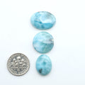 Larimar stone cabochons, cut and polished, blue and white gemstones on a white background, with a US dime for scale