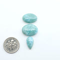 Larimar stone cabochons, cut and polished, blue and white gemstones on a white background, with a US dime for scale