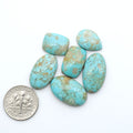 Pilot Mountain Turquoise cabochons, blue-green gemstones with natural matrix on a white background with a US dime for scale