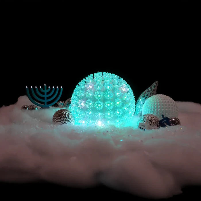 Decorative scene with glowing teal sphere, menorah, and other ornaments on a dark background