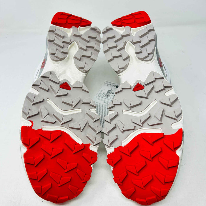 The Salomon XT-4K Kith Kithmas White Red sneakers rest on a black Kith box, with an extra laces bag. The shoes are 100% authentic, showcasing red accents and branding details.