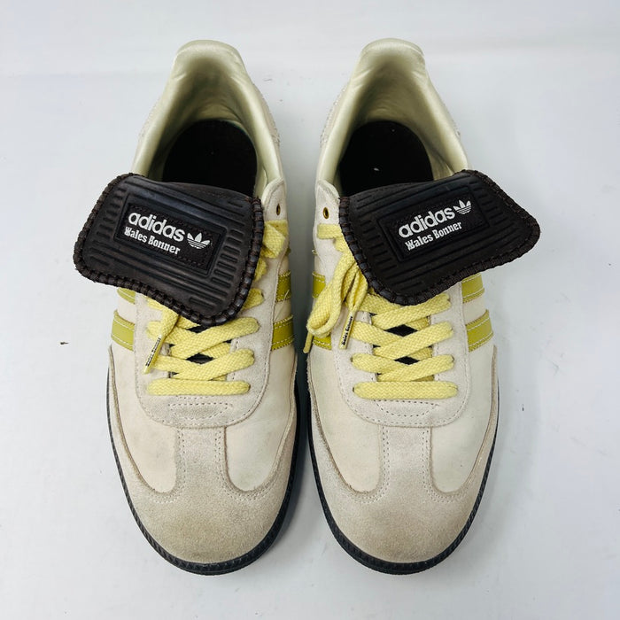 The 2023 adidas Samba Wales Bonner Ecrtin Brown sneakers feature beige uppers with three yellow stripes, a brown logo flap, and black soles. Despite general wear, the side and tongue branding stays distinct. Theyre displayed side by side on a white background.