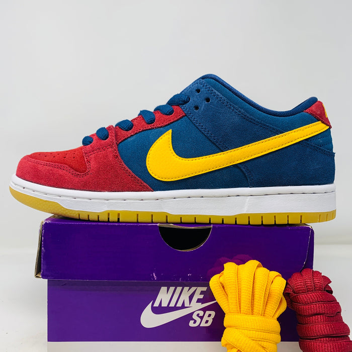 Nike SB Dunk Low Barcelona sneaker in red, blue, and yellow on a purple Nike SB box with extra shoelaces.