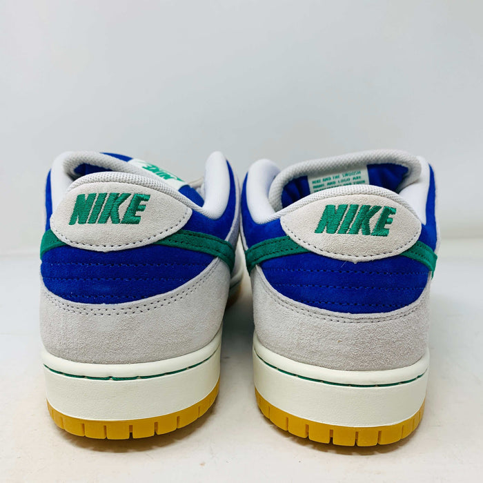 The Nike SB Dunk Low Hyper Royal Malachite, a fresh pair of white and blue sneakers with a green swoosh and gum sole, includes extra laces and is presented atop a purple Nike SB shoe box.