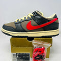 Nike SB Dunk Low Iron Man sneaker with black and brown upper, red Nike swoosh, cream laces, and additional red laces in a bag on a gold Nike box