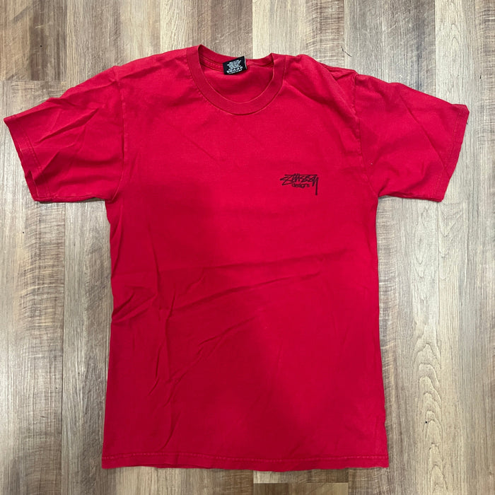 Preowned red Stussy Designs tee with back logo on wooden floor