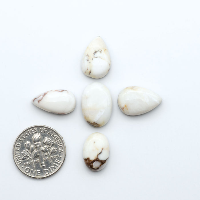 Wild Horse Magnesite cabochons, white gemstones with brown matrix on a white background, with a US dime for scale
