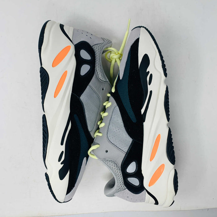 A Yeezy 700 Waverunner with a multicolor scheme of gray, black, teal, and orange rests on a Yeezy Boost 700 Made by Adidas box. Sales are final on these authentic shoes.