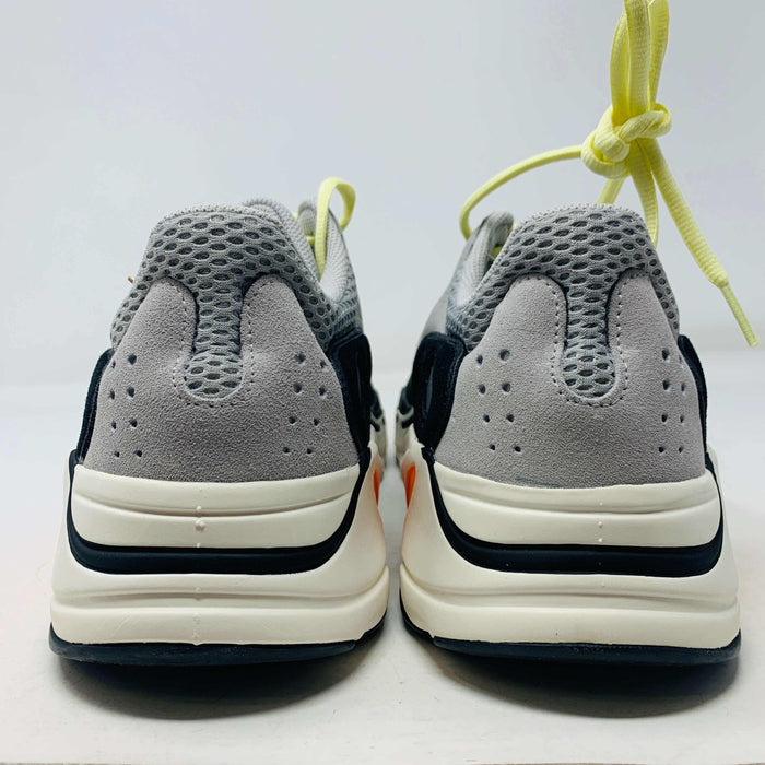 A Yeezy 700 Waverunner with a multicolor scheme of gray, black, teal, and orange rests on a Yeezy Boost 700 Made by Adidas box. Sales are final on these authentic shoes.