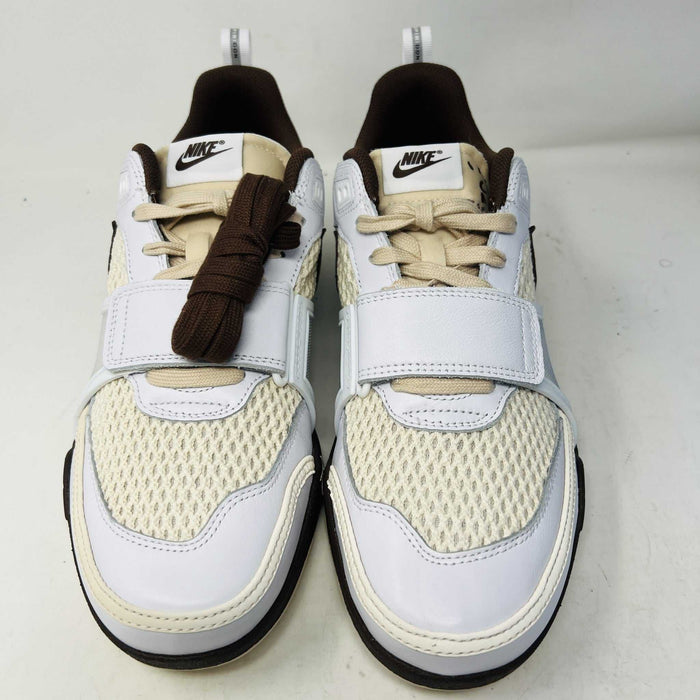 The Nike Zoom Field Jaxx Travis Scott Light Chocolate sneaker showcases a white and brown design with mesh and leather textures, Velcro strap, brown laces, and a prominent brown swoosh. It sits on a blue Nike shoebox.