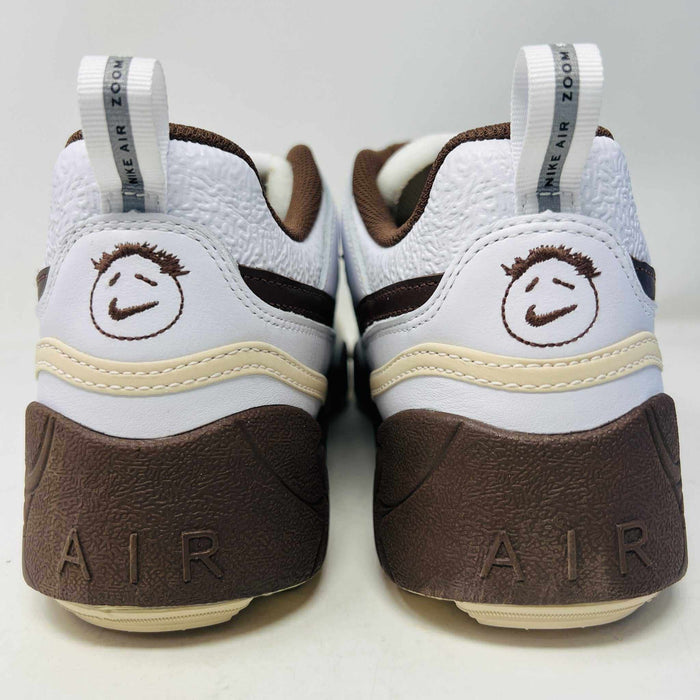 The Nike Zoom Field Jaxx Travis Scott Light Chocolate sneaker showcases a white and brown design with mesh and leather textures, Velcro strap, brown laces, and a prominent brown swoosh. It sits on a blue Nike shoebox.